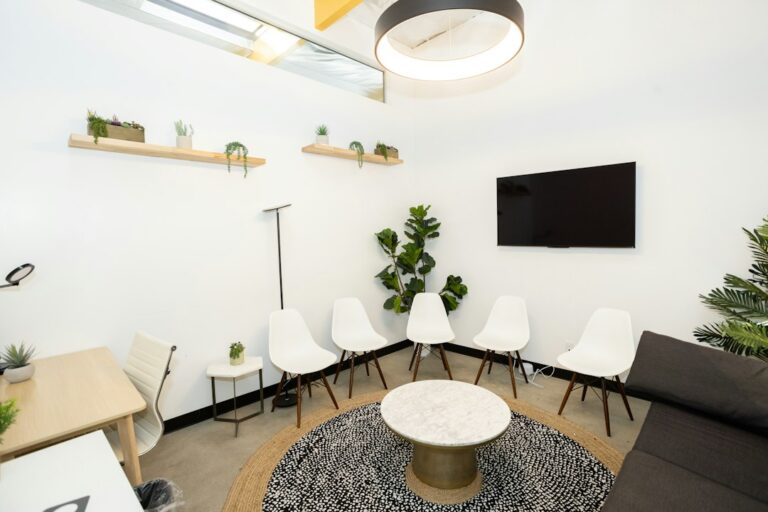 Bright modern waiting room with white chairs and plants at an OB-GYN practice