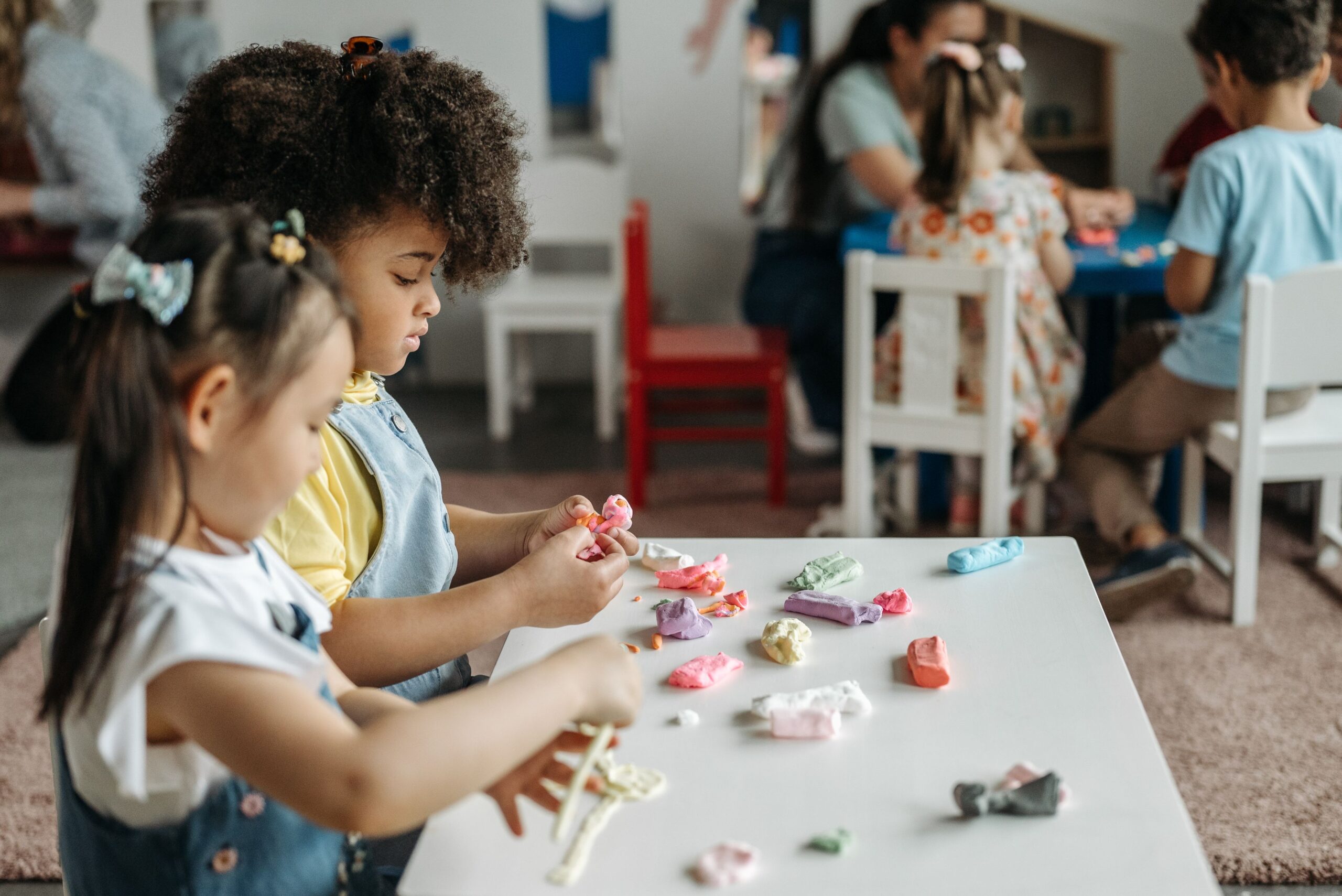 Preschool children at a table playing with colorful clay, building fine motor skills