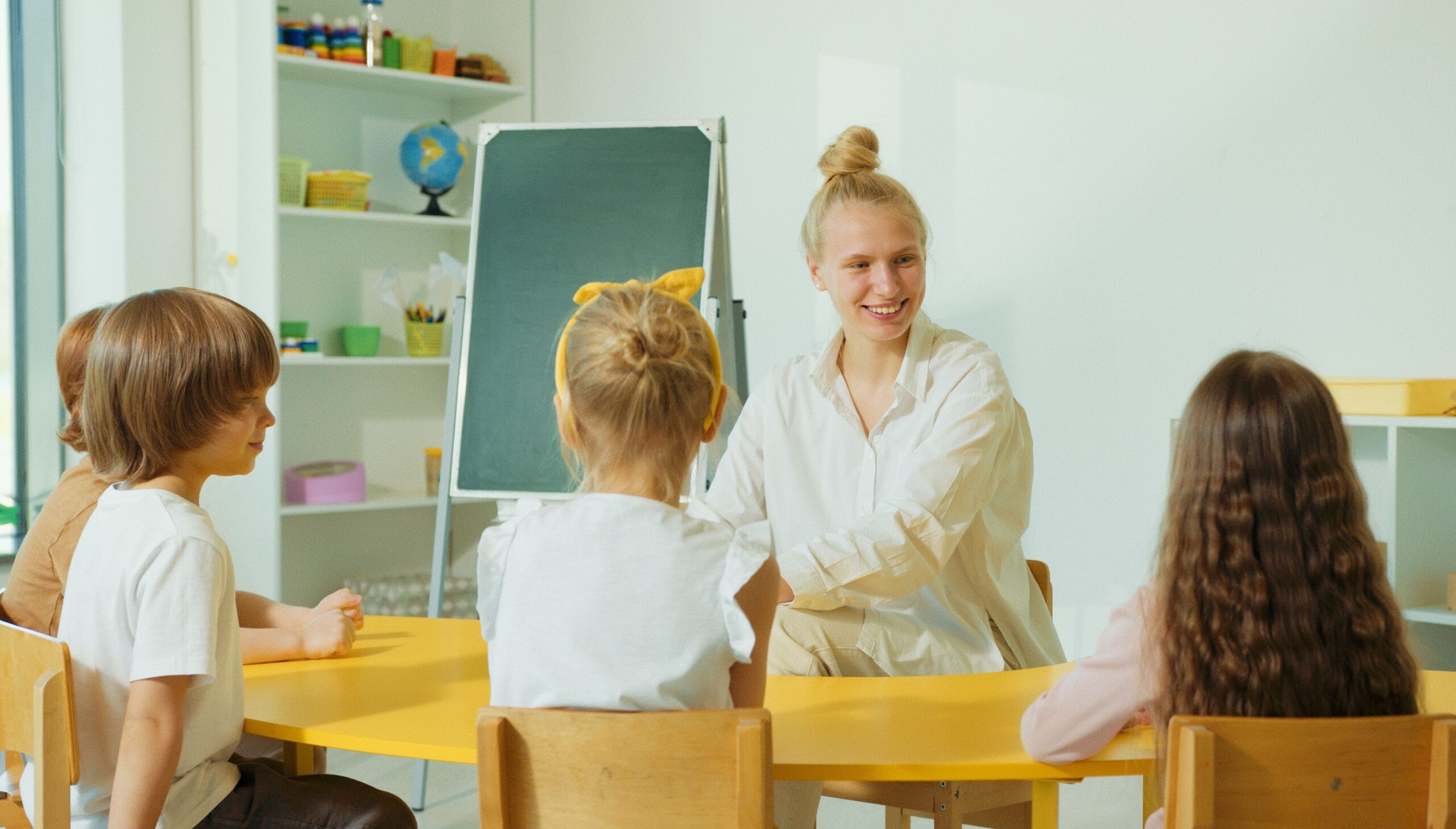 Preschool teacher engaging with children in a colorful, well-equipped classroom