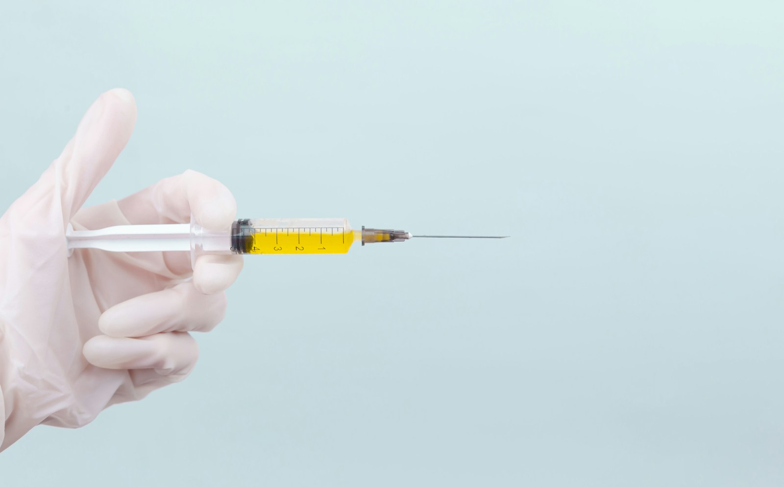 Gloved hand holding a syringe prepared for an allergy immunotherapy injection