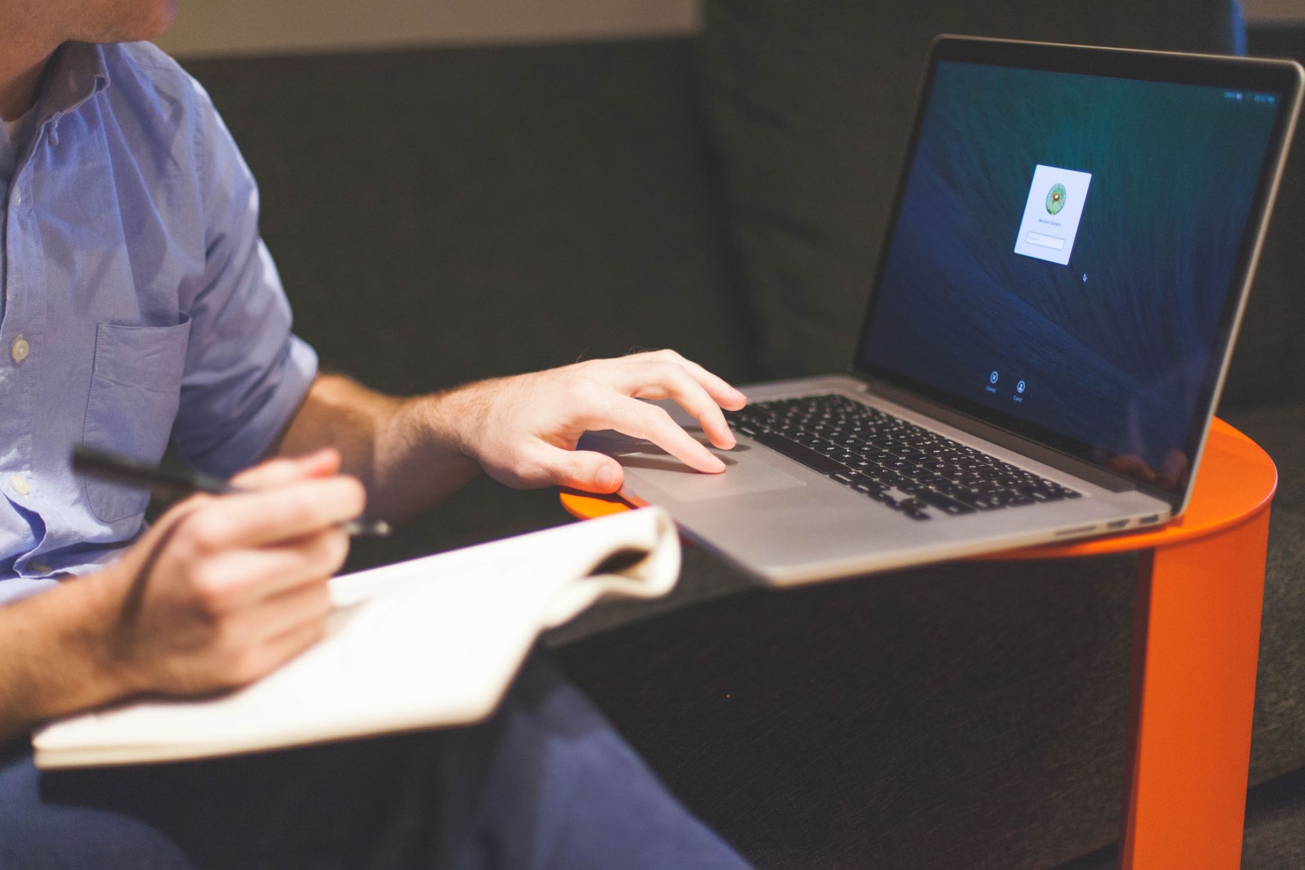 A person drafting blog content on a laptop beside handwritten notes