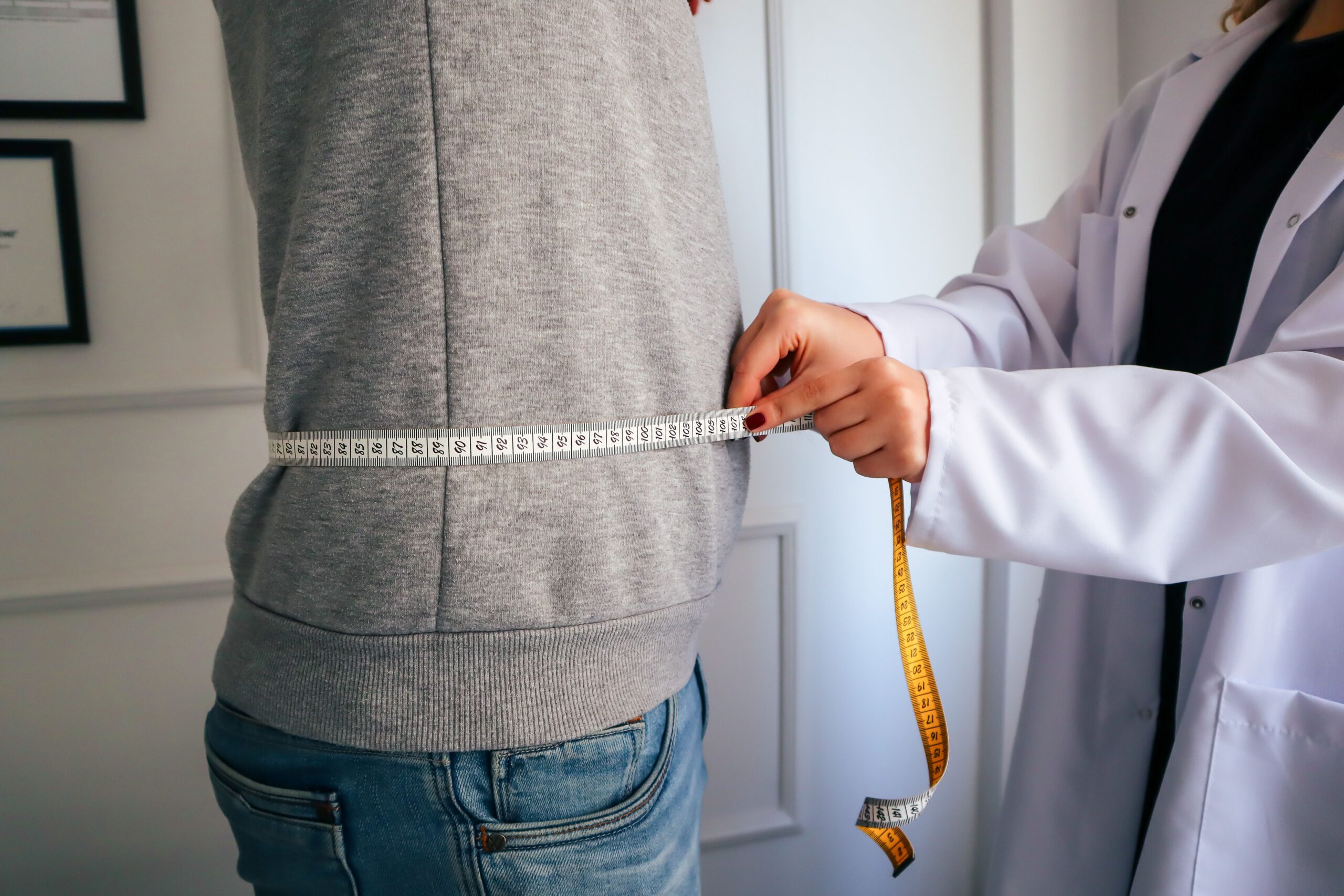 Clinician measuring a patient's waist during a weight loss clinic check-in