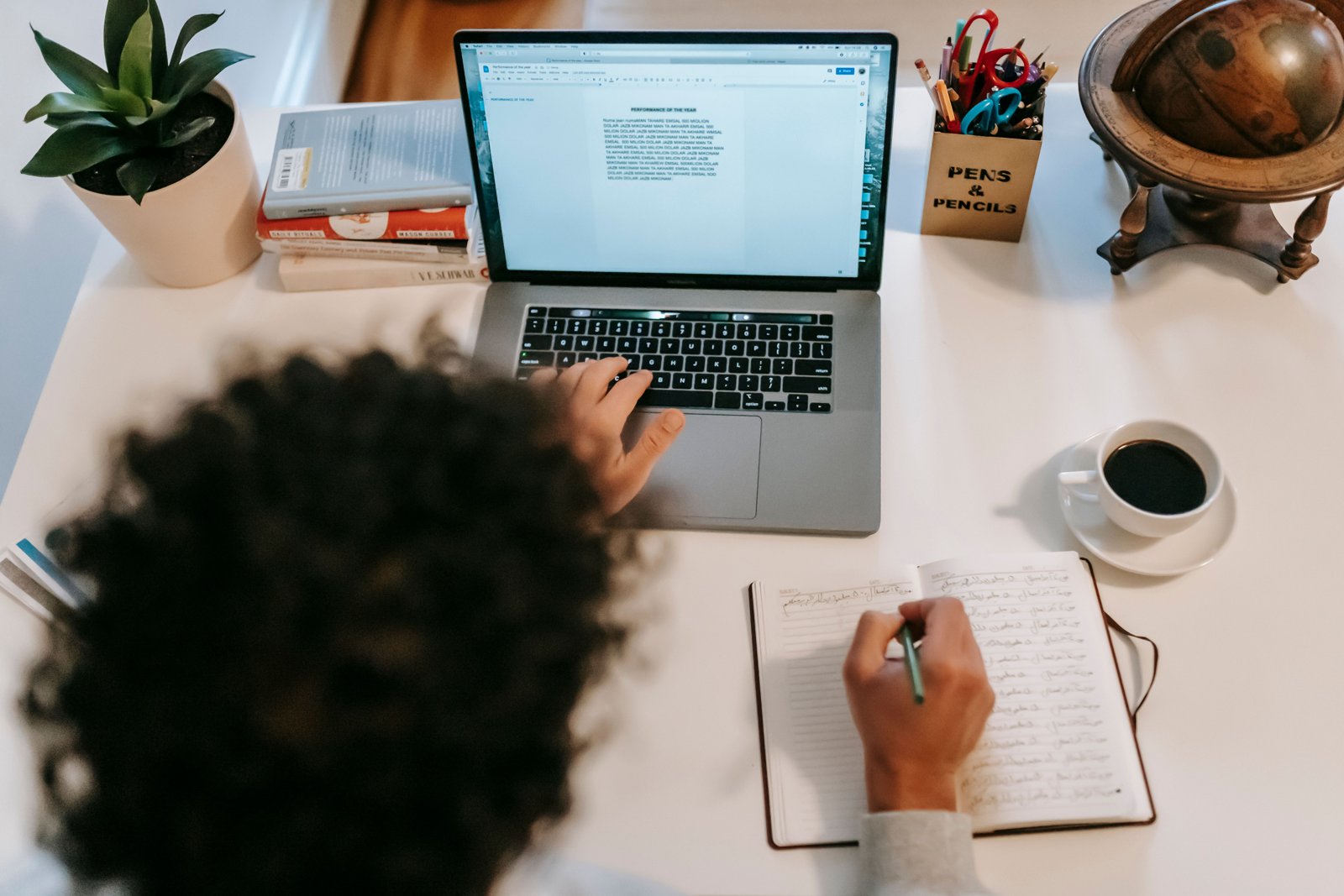 A writer typing a blog post on a laptop with coffee at a desk